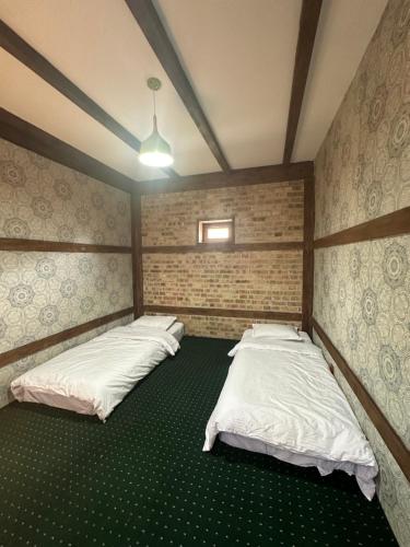 2 camas en una habitación con alfombra verde en 阿拉木图市和平民宿, en Kalkaman