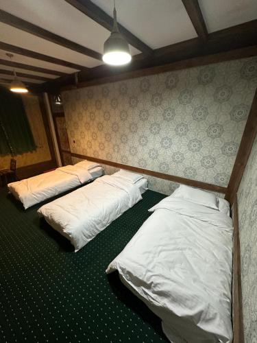 3 posti letto in una stanza con lenzuola bianche di 阿拉木图市和平民宿 a Kalkaman