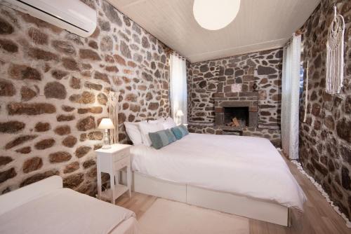 ein Schlafzimmer mit einer Steinmauer, einem Bett und einem Kamin in der Unterkunft peaceful place in Anítsaion