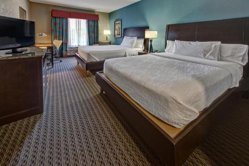 a hotel room with a large bed and a flat screen tv at Hilton Garden Inn Midtown Tulsa in Tulsa