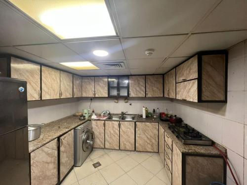 uma cozinha com armários de madeira, um lavatório e uma máquina de lavar louça em Furnished Regular Room in shared Apartment em Abu Dhabi