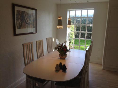 a dining room table with a vase of flowers on it at Rane Ladegaard in Ebeltoft