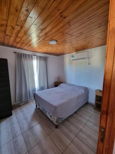 sypialnia z łóżkiem i drewnianym sufitem w obiekcie Terrazas de Estancia w mieście Villa Carlos Paz