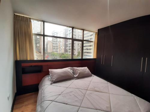 um quarto com uma cama grande e uma janela grande em CONFORTABLE Y ELEGANTE DEPARTAMENTO em Quito