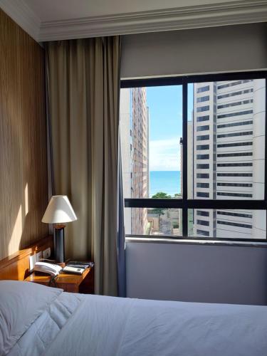 ein Hotelzimmer mit einem Bett und einem großen Fenster in der Unterkunft Apartamento caminho do mar in Fortaleza