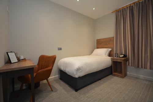 Habitación de hotel con cama, escritorio y escritorio. en The Rugby Hotel en Rugby