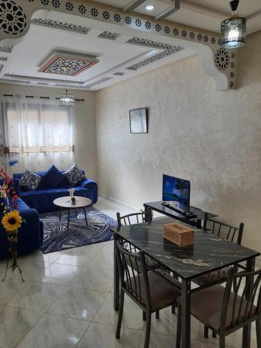 a living room with a table and a blue couch at Appartement Dar Meknès in Meknès