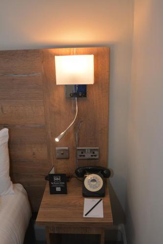 a lamp on a table next to a bed at The Rugby Hotel in Rugby