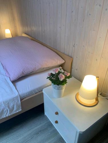 ein Bett mit einem Tisch mit einer Lampe und einer Topfpflanze in der Unterkunft Chez Ninfa in Villeret