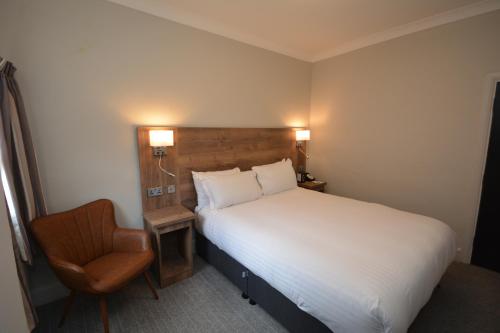 a hotel room with a bed and a chair at The Rugby Hotel in Rugby