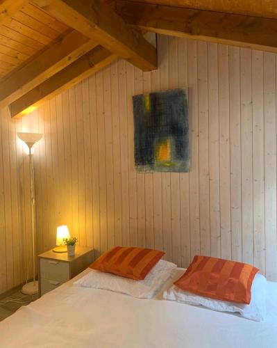 ein Schlafzimmer mit einem weißen Bett mit zwei orangefarbenen Kissen in der Unterkunft Chez Ninfa in Villeret