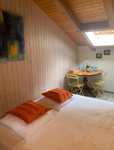 a bedroom with a bed with orange pillows and a table at Chez Ninfa in Villeret
