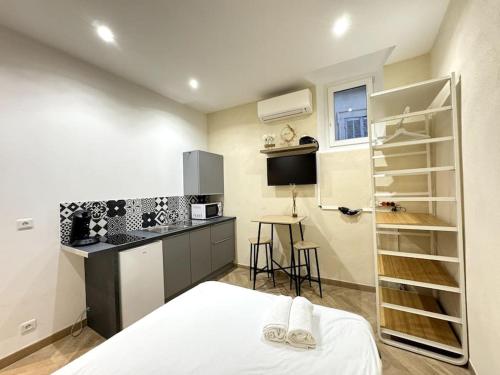 Cet appartement comprend une chambre avec un lit blanc et une cuisine. dans l'établissement Studio au coeur du Vieux Port avec Clim, à Marseille