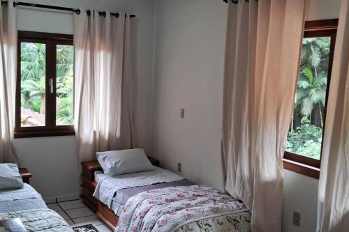 1 dormitorio con 2 camas y 2 ventanas en Sítio Som das Águas en Benedito Novo