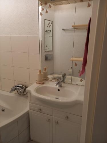 a bathroom with a sink and a mirror and a tub at Ferienwohnung Enz, 3 OG. in Pforzheim