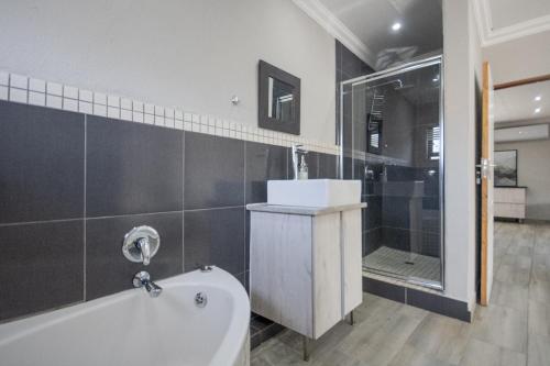 a bathroom with a tub and a shower and a sink at Apartment at Magalies Edge in Hartbeespoort