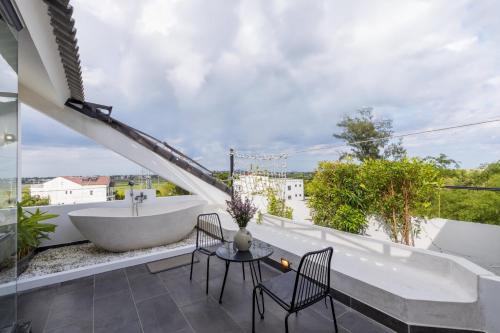 a balcony with a tub and a table and chairs at Charm Champion Villa Hoian in Hoi An
