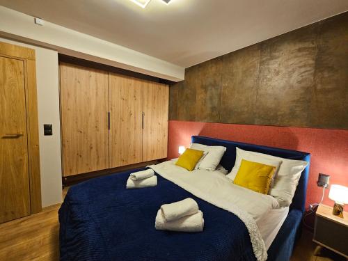 a bedroom with a large blue bed with yellow pillows at Apartament RS6 in Zakopane