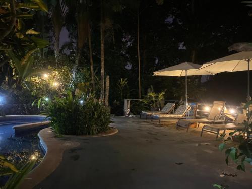 a swimming pool at night with chairs and umbrellas at Villas en el Bosque in Ojochal