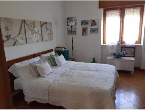 - une chambre dotée d'un grand lit avec des draps et des oreillers blancs dans l'établissement Casa i Quattro Alberi, à Montemiletto