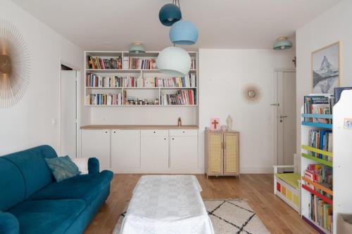 een woonkamer met een blauwe bank en boekenplanken bij Spacious nest just outside Paris in Levallois-Perret