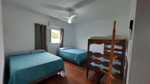 a bedroom with two beds and a ceiling fan at Suites 500m Praia da Enseada in Guarujá