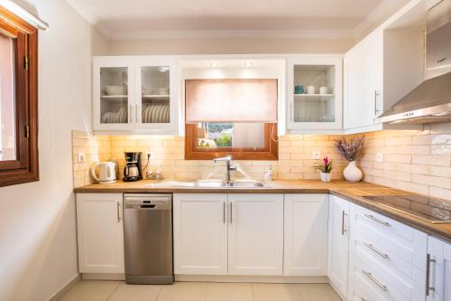 a kitchen with white cabinets and a sink and a window at Villa Danai in Karpathos Town