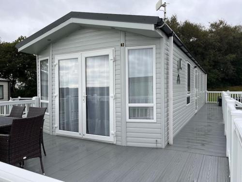 a white house with a deck with a table and chairs at The Cornish hottub escape in St Austell