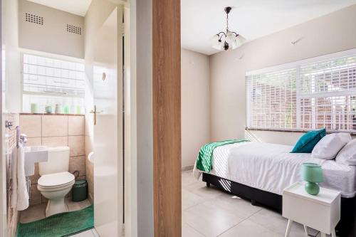 1 dormitorio con cama, aseo y lavamanos en The Hide Out - Home away from home, en Johannesburgo