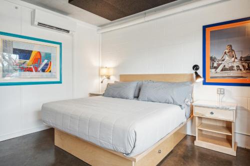 a white bedroom with a bed and a night stand at Boutique Vera Hotel in the Heart of Folly Beach in Folly Beach