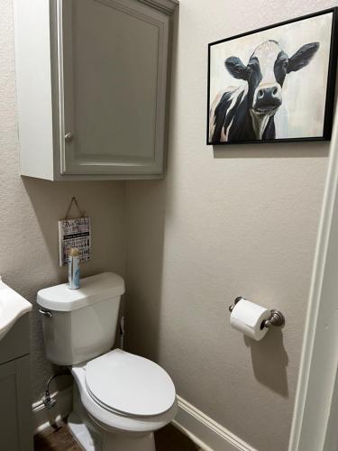 a bathroom with a toilet and a picture of a cow at The Retreat at Hempstead in Hempstead