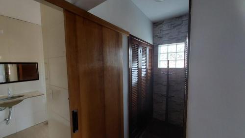 a bathroom with a wooden door and a sink at Suites 500m Praia da Enseada in Guarujá
