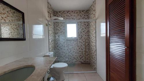 a bathroom with a sink and a toilet and a window at Suites 500m Praia da Enseada in Guarujá