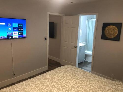 a bedroom with a bed and a flat screen tv at City First Story Apartments & Cottage in Fort Lauderdale