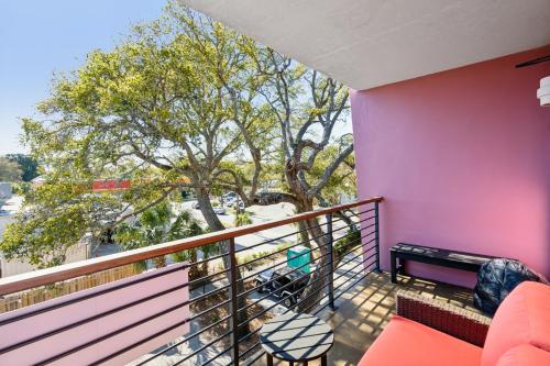 a balcony with a pink wall and a tree at Boutique Vera Hotel in the Heart of Folly Beach in Folly Beach