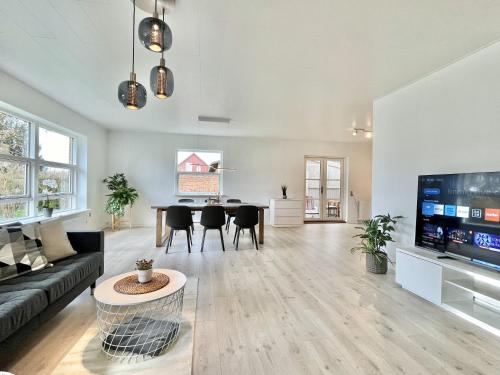 een woonkamer met een bank en een tafel bij Stunning & Renovated 130sqm Villa only 5 min by car from sandy beaches in Åkirkeby