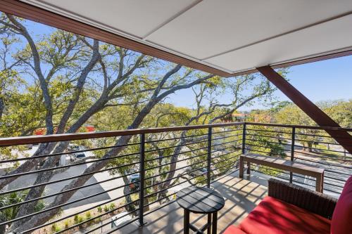 a balcony with a red couch and a stool at Boutique Vera Hotel in the Heart of Folly Beach in Folly Beach