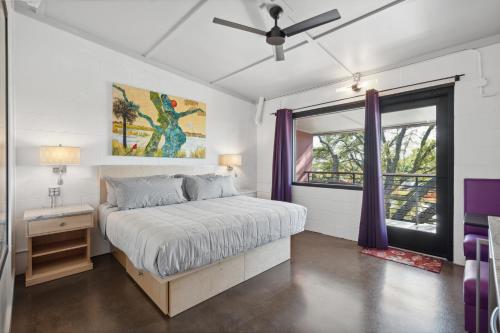 a bedroom with a bed with purple curtains and a window at Boutique Vera Hotel in the Heart of Folly Beach in Folly Beach