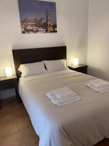a bedroom with a large bed with two towels on it at Apartamento Puerta del Perdón in Constantina
