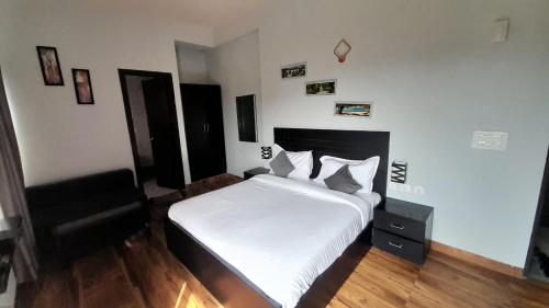 una camera con un letto bianco e una sedia nera di Vrindavan serenity hotel & suites a Vrindāvan