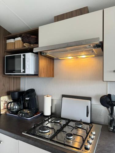 a kitchen with a stove top and a microwave at Prachtig chalet de ZEE STER in Westerland
