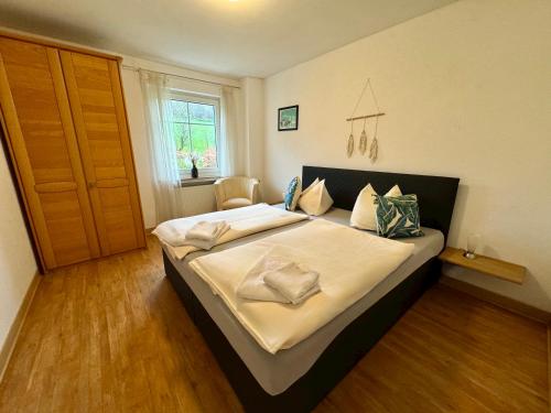 een slaapkamer met een groot bed met witte lakens bij Schnütgenhof Appartements in Attendorn