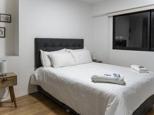 a bedroom with a white bed with a phone on it at 2BR in Center of Miraflores La Paz in Lima