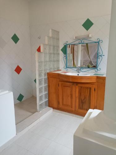 La salle de bains est pourvue d'un lavabo et d'un miroir. dans l'établissement Villa Savana, à La Somone