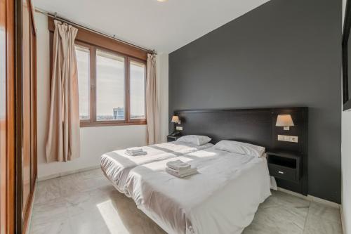 una camera con un grande letto con testiera nera di SevillaHome-Apartamento complejo piscina parking a Siviglia