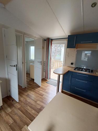 a kitchen with blue cabinets and a table in a room at MOBIL HOME climatisé camping NOVELA PORT LA NOUVELLE in Port-la-Nouvelle