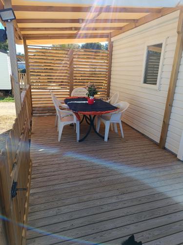 un patio avec une table et des chaises sur une terrasse dans l'établissement MOBIL HOME LUCKY climatisé camping NOVELA PORT LA NOUVELLE, à Port-la-Nouvelle
