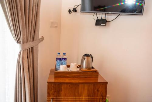 a television on a wall next to a table with water bottles at Grand Argyle Resort in Hatton