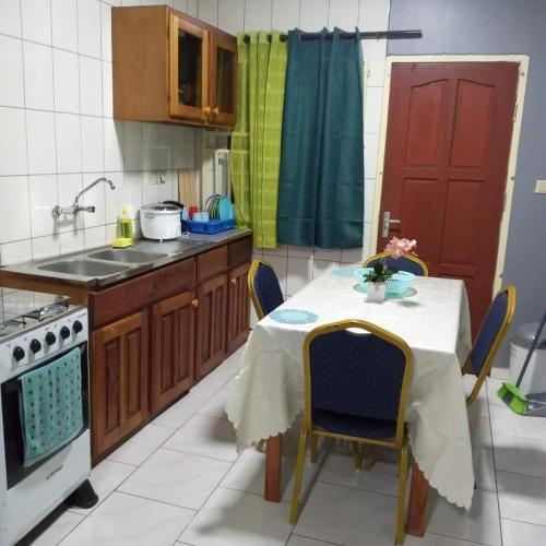 cocina con mesa con sillas y fregadero en SRB apartments en Paramaribo
