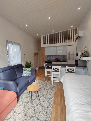 a living room with a blue couch and a kitchen at Bålsta Studio Houses in Bålsta